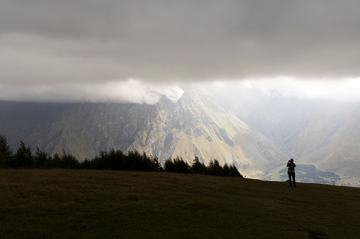 Tourist woman hiking in Georgia on Kazbek moutain in Caucasus moutains peak in summer