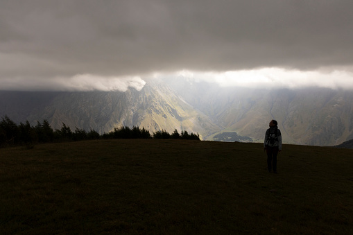 Tourist woman hiking in Georgia on Kazbek moutain in Caucasus moutains peak in summer