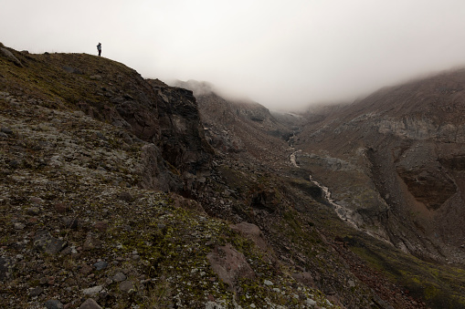 Woman on mountain meadow hiking in Caucasus mountains alone during summer foggy day near Kazbek peak