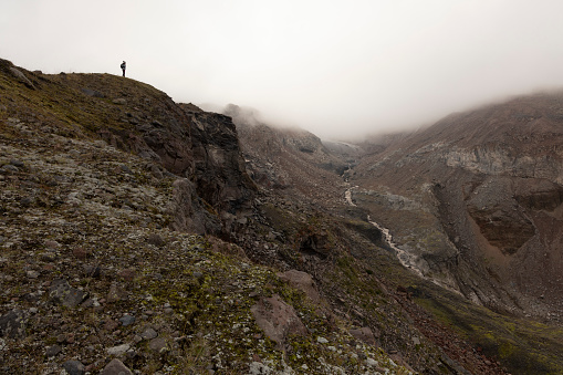 Woman on mountain meadow hiking in Caucasus mountains alone during summer foggy day near Kazbek peak