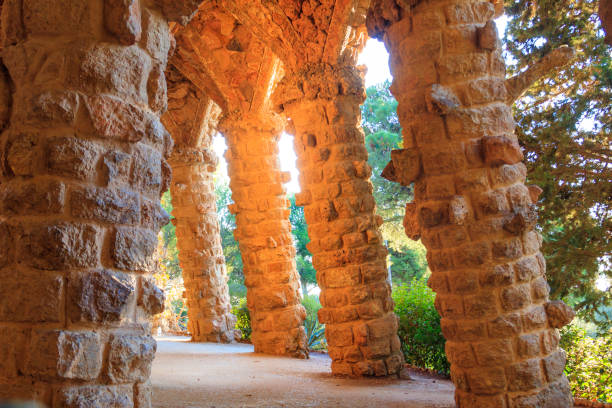 Gaudí's unique stone viaducts, characterized by organic architecture draped in vibrant magenta bougainvillea and set lush palm trees