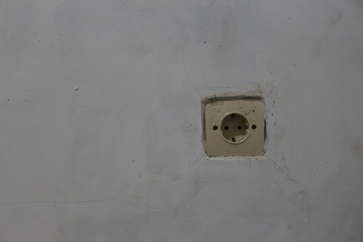 Plug socket without cover, stick-on model on white wall