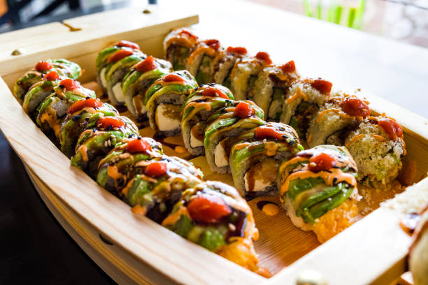 Sushi Roll Boat Served with Wasabi and Ginger - Sushi rolls presented on wooden boat in Asian restaurant.