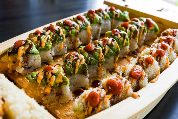 Sushi Roll Boat Served with Wasabi and Ginger - Sushi rolls presented on wooden boat in Asian restaurant.