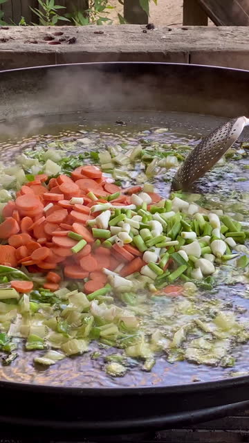 Frying chopped vegetables in paella pan