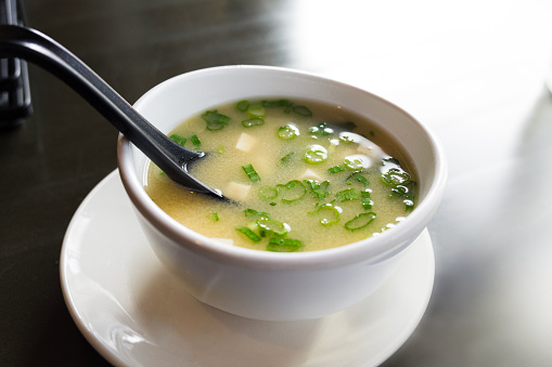 Traditional Japanese Miso Soup - Closeup of bowl with spoon. Fresh hot soup with seaweed, tofu and fish broth.