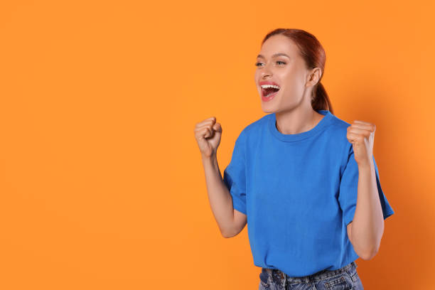 istock Excited sports fan celebrating on orange background, space for text 1920065111