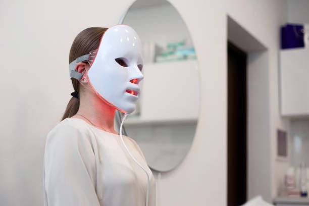 istock Beautiful young woman getting a led light therapy mask treatment for her face 1920066112