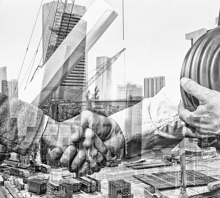 Double exposure of contractors handshaking at a construction site closing a deal with a blueprint in the foreground. The image is superimposed over a construction site. The city is Miami.
