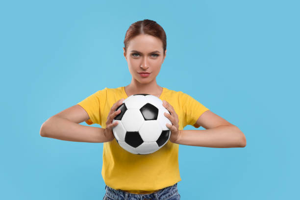 istock Fan holding football ball on light blue background 1920073034