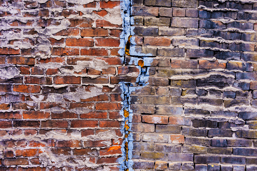 Old Brick Wall with Cracks and Textured Detail Background - Od building with colorful cracks and detail.