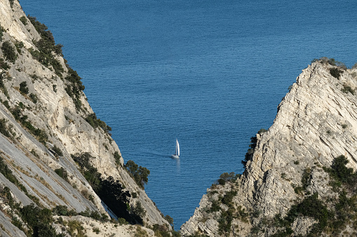 An idillyc view of Conero Riviera with a Sailboat sailing among rocks