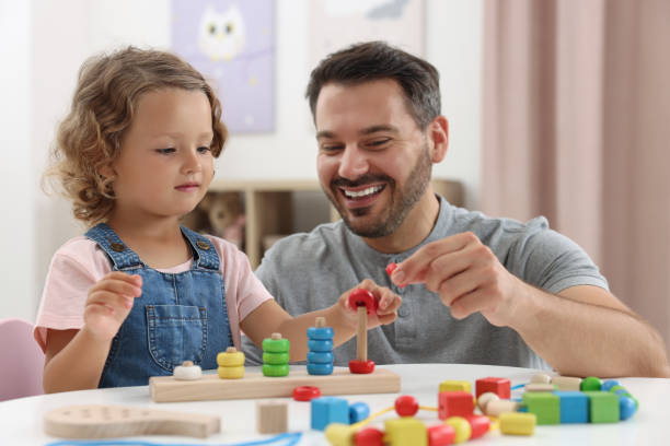 istock Motor skills development. Father and daughter playing with stacking and counting game at table indoors 1920104880
