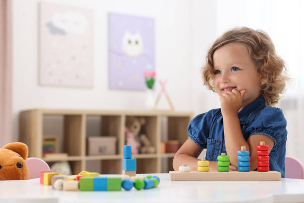 istock Motor skills development. Little girl playing with stacking and counting game at table indoors 1920105928