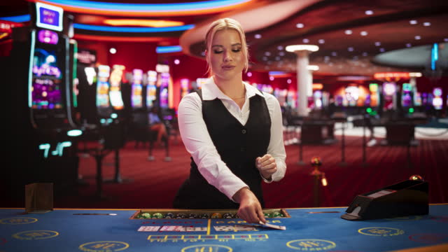 Professional Female Croupier in Casino Dealing Playing Cards on a Baccarat Table. Beautiful Dealer of a Live Online Casino Reveals Winning Results of the Card Game Bets, Looking at Camera. Static Shot
