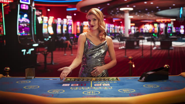 Portrait of a Female Croupier Looking at the Camera and Sharing the Results of a Baccarat Card Game. Beautiful Dealer in the Live Online Video Casino Revealing a Winning Hand. Static Shot