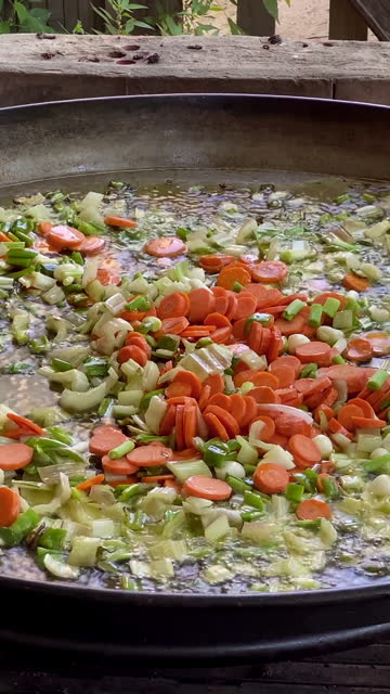 Frying chopped vegetables in paella pan