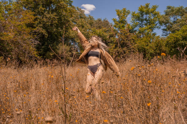 Beauty blonde woman posing over bright daylight with bikini and jacket.