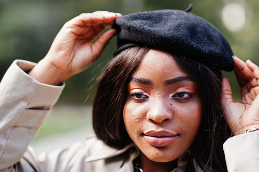 Close up portrait of fashionable african american woman wear beret and coat posing outdoor.