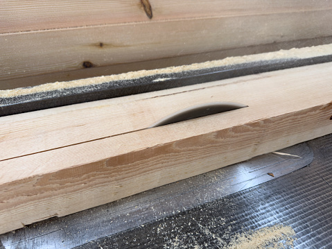 Carpenter cutting wooden boards for furniture in his workshop.Carpenter's circular Saw.