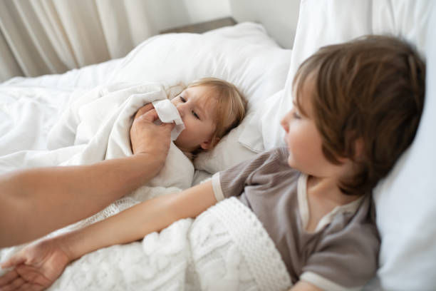 istock Siblings sick at home with flu, cold, coronavirus, bronchitis or pneumonia, virus or infection, father helping his child to blow nose 1920289666