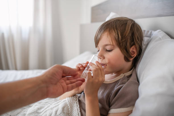 istock Father giving water to his child sick with cold or flu 1920291752