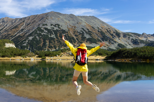 Girl jumping on a dock in front of lakes and mountains.
