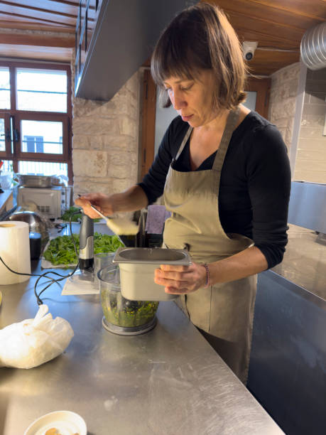istock Professional female chef preparing food in modern restaurant kitchen. He makes appetizers with vegetables in the blender. 1920322864