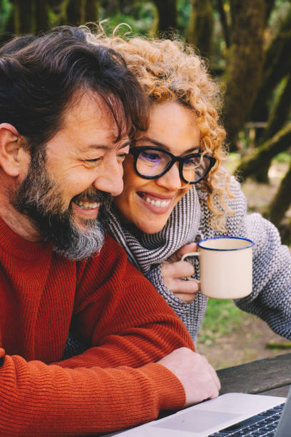 istock Happy modern couple use together laptop computer outdoors with trees and woods in background - video call and smart remote working activity lifestyle concept with cheerful people and technology 1920331747