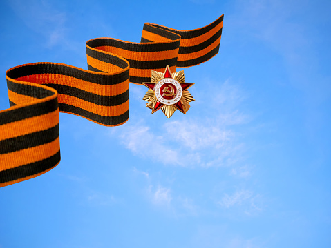 9th May. The concept of the Great Victory Day of 1945. St. George's ribbon on a clear sky background. The inscription on the badge of the Patriotic War