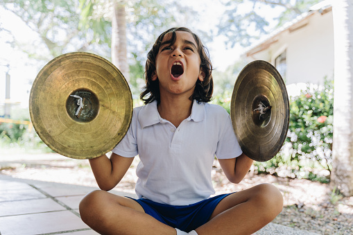 Child boy playing cymbals outdoors