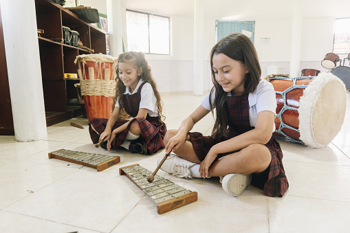 Child girls playing xylophone in the school classroom