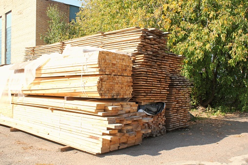 Close-up of wooden planks at lumber warehouse. Storage shelves with panel in lumberyard. Background of boards on shop. Processed timber blocks products in market. Raw wood drying in carpenter workshop