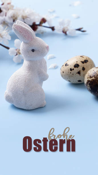 istock Frohe Ostern text Happe Easter in German. Rabbit with eggs and flower branch on a blue banner background 1920378971