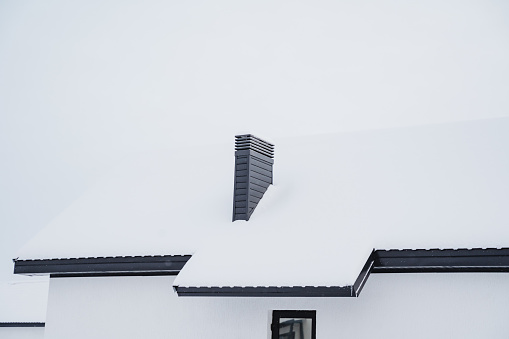 Chimney, chimney on the roof of the house, metal chimney, snow on the roof, country house. High quality photo