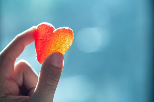 Little boy with heart-shaped sweets in hands.