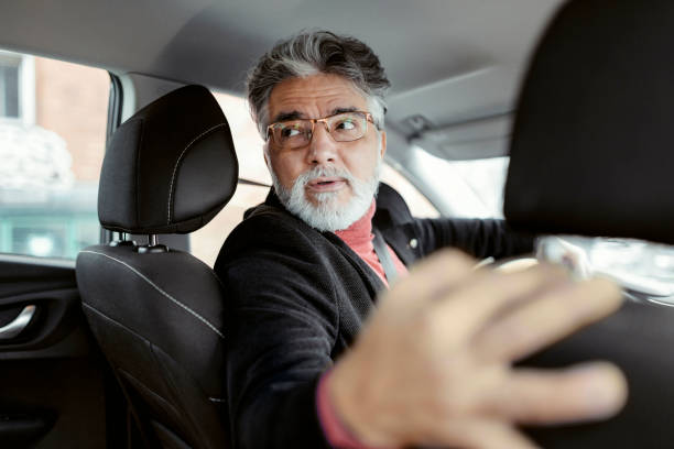 homme mûr conduisant sa voiture en marche arrière - car driving men reversing photos et images de collection