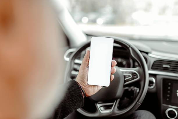 Smart phone device in male hand, mock up with blank white screen. Man sitting in car and holding smartphone