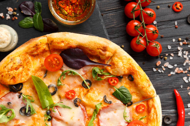 istock Pizza with ham on a black stone plate on a dark wooden background, top view 1920472669
