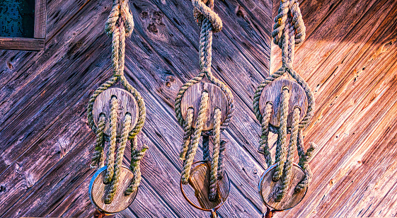 Three weathered antique deadeye pulleys hang from a wharf building in Florida.