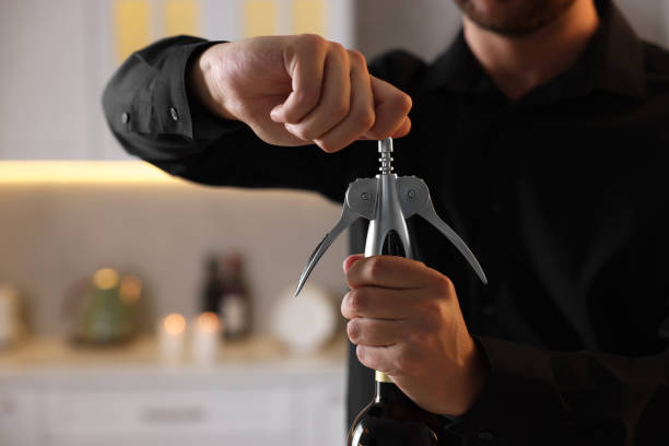 istock Man opening wine bottle with corkscrew indoors, closeup 1920503134