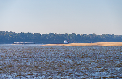 Panorama of sand banks due to extreme low water conditions on Mississippi river in October 2023 with a large barge rounding a bend near Greenville, MS