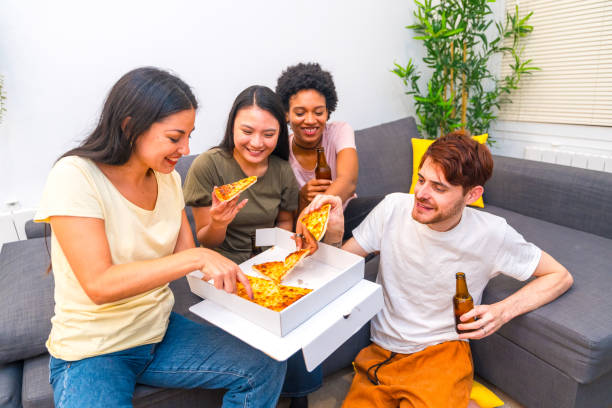 istock Multi-ethnic flatmates enjoying pizza and beer at home 1920569777
