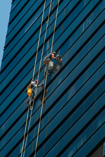 Bogota . Colombia 11  de Julio de 2023:Men with spring harness cleaning, blue building