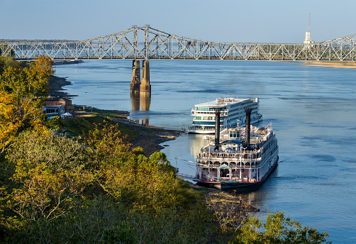 Natchez, MS - 26 October 2023: Viking Mississippi cruise boat and traditional American Queen riverboat docked under the hill