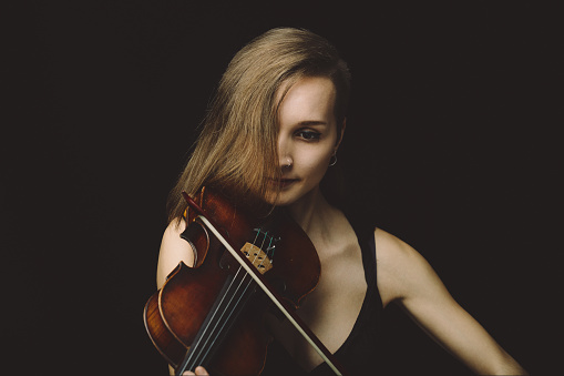 One person of aged 20-29 years old who is beautiful caucasian female violinist standing in front of white background wearing pants who is showing cool attitude and holding violin