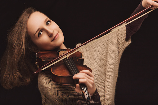 oung female violinist with a passionate gaze plays her instrument, the embodiment of classical music's enduring charm