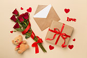 Valentines day gifts with red roses on color background, top view