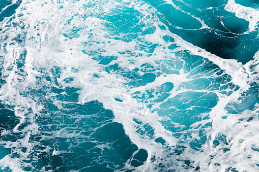 Taken off the side of a large ship, this image depicts powerful blue waves as the wind blows them across the vast ocean near Alaska.