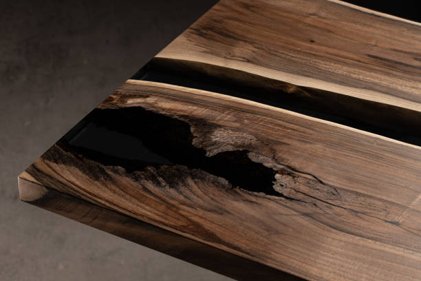 The table is covered with epoxy resin and varnished. Luxury quality wood processing. Wooden table on a dark background. Business proposal concept.
